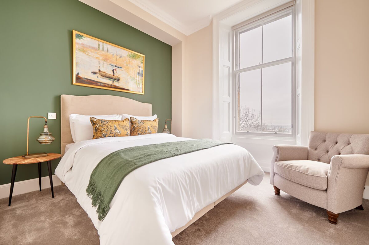 Сучасний дизайн інтер'єру з білими стінами, зеленим диваном та рослинами у світлій кімнаті