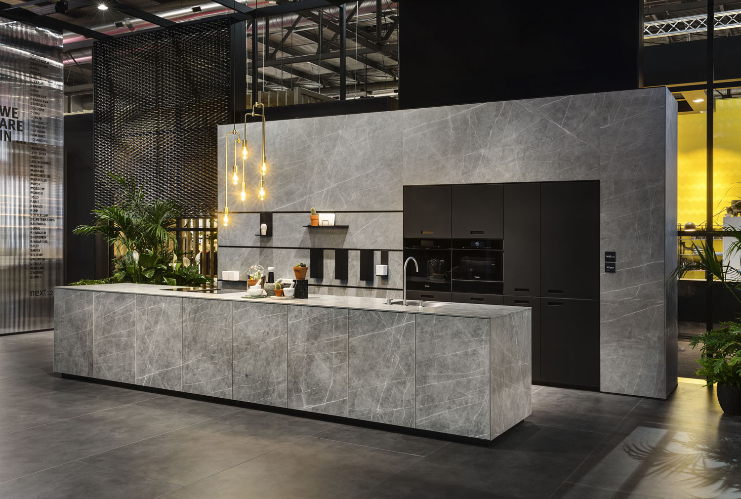 Сучасна кухня з бетонною стільницею, дерев'яними шафами та скандинавським дизайном освітлення.