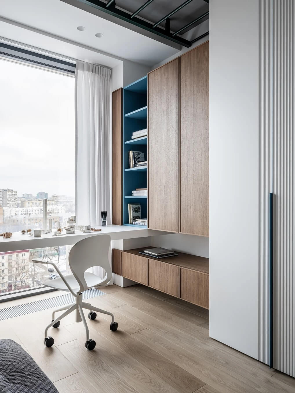 Світле робоче місце біля вікна з мінімалістичним дизайном та зеленими рослинами