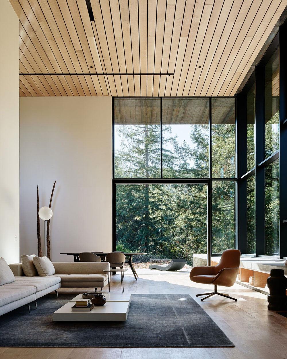 Панорамні вікна в будинку з каміном, що створює затишну атмосферу. Вікна в підлогу з видом на сад.