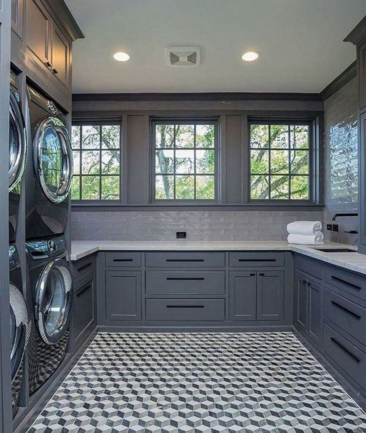 Стильна пральня в будинку з прасувальною дошкою та полицями для миючих засобів.