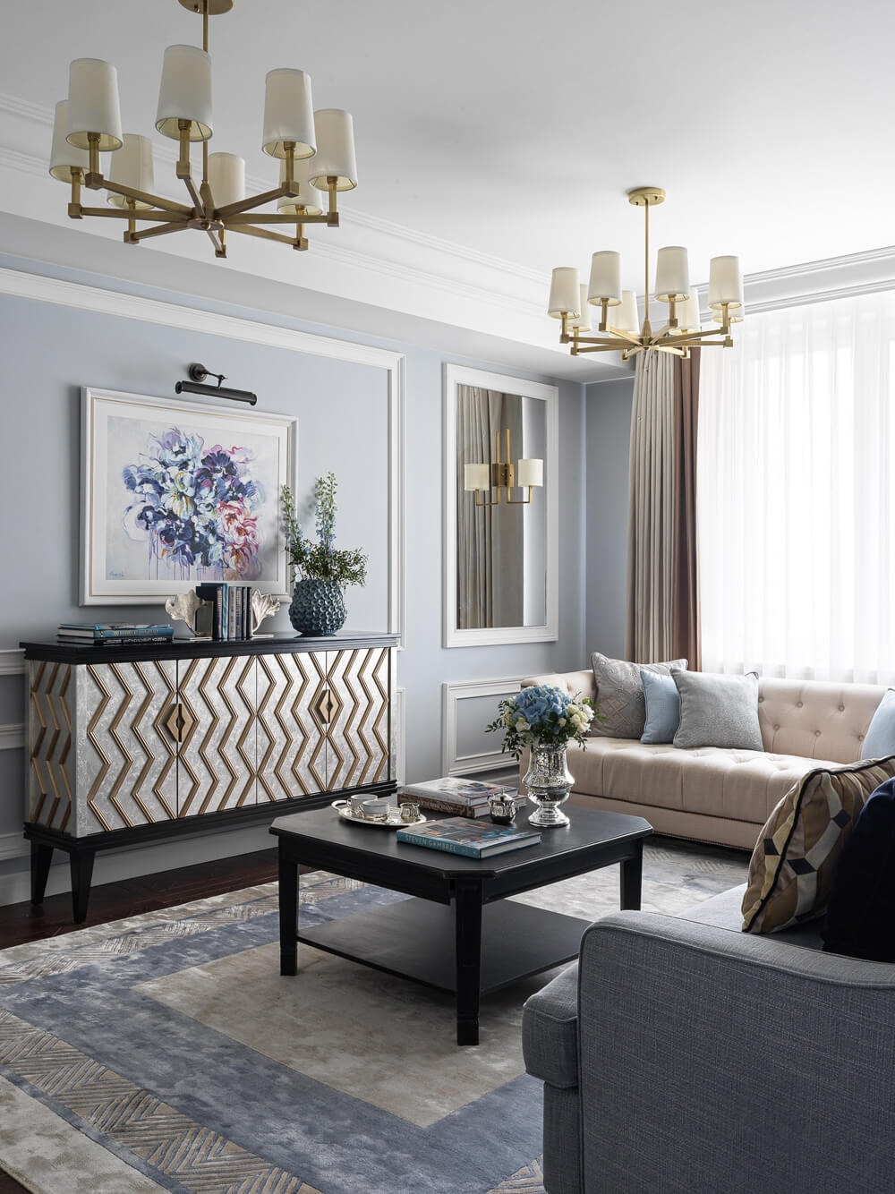 Світла вітальня в стилі сучасної класики з великими вікнами та зручними меблями.