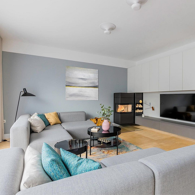 Світла вітальня з сучасною стінкою, що включає закриті шафи та відкриті полиці для декору.