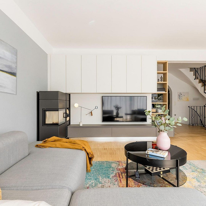 Сучасний дизайн вітальні з великою стінкою, що поєднує темні та світлі відтінки дерева.