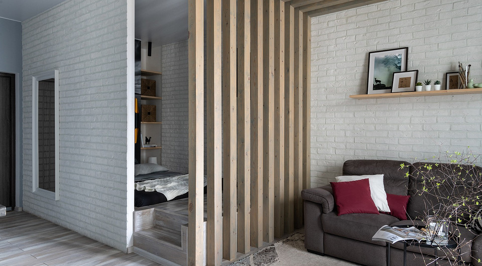 Функціональний інтер'єр з подіумом для зонування простору та створення додаткового місця зберігання.