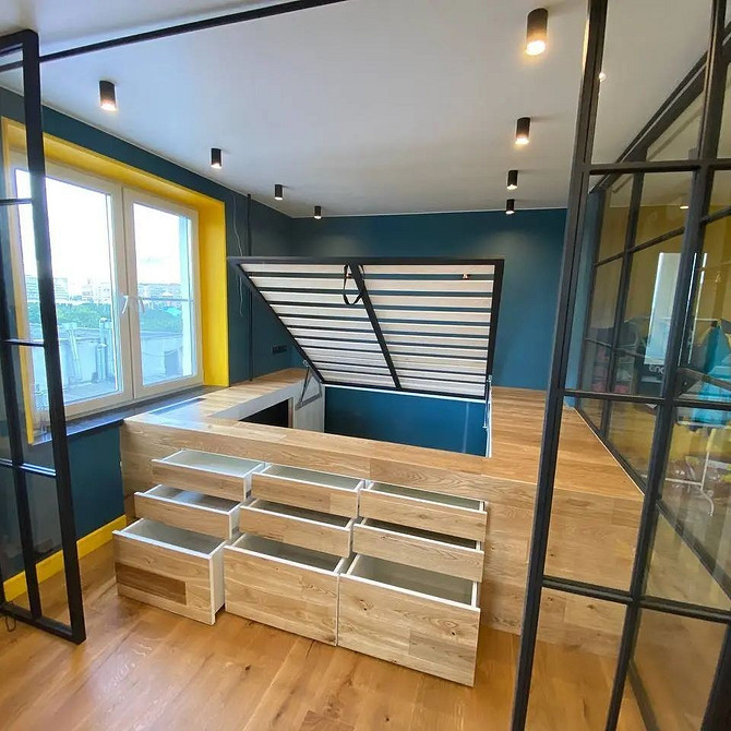 Інтер'єр з подіумом, що переходить у зону відпочинку з м'якими подушками та килимом.