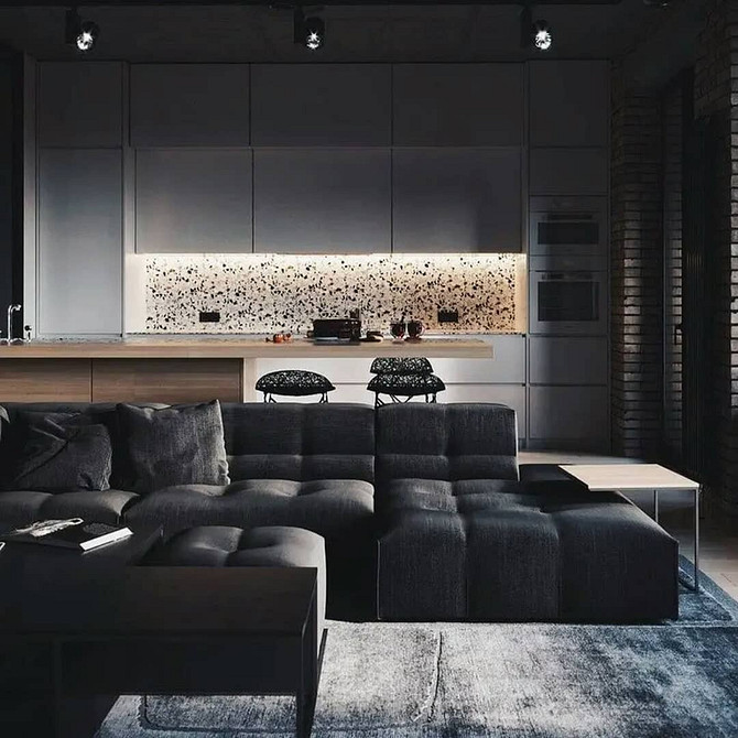 Вітальня з темним шкіряним диваном, світлими подушками та декоративним освітленням