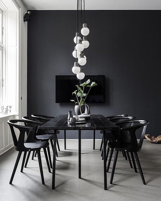 Елегантна їдальня з темним дерев'яним столом і стільцями, освітлена люстрою