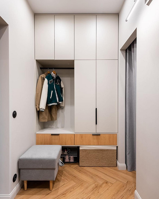 Інтер'єр спальні з білим ліжком, тумбочками та текстилем у пастельних тонах.