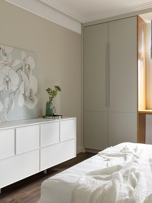 Дизайн сучасної спальні: білі меблі, дерев'яна підлога та текстиль у пастельних тонах.