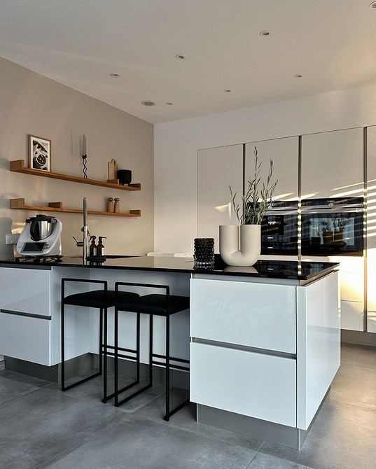 Дизайн кухні з білими фасадами, інтегрованою технікою та сучасним освітленням для комфорту.