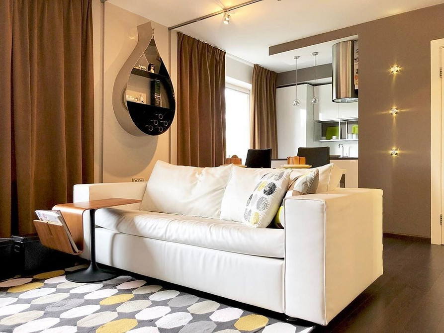 Світла вітальня з білими меблями та великими вікнами, наповненими природним світлом.