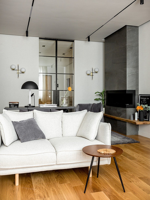 Стильний білий диван з дерев'яними ніжками в світлому інтер'єрі вітальні