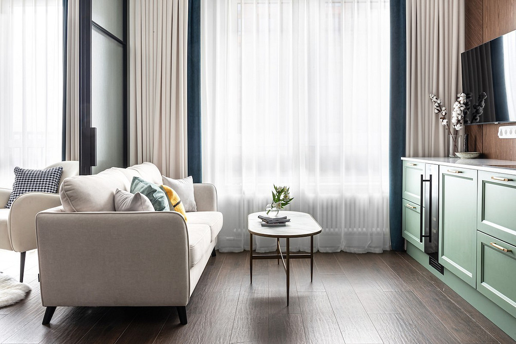 Вітальня з білим диваном, зеленими рослинами та дерев'яними меблями в еко-стилі.