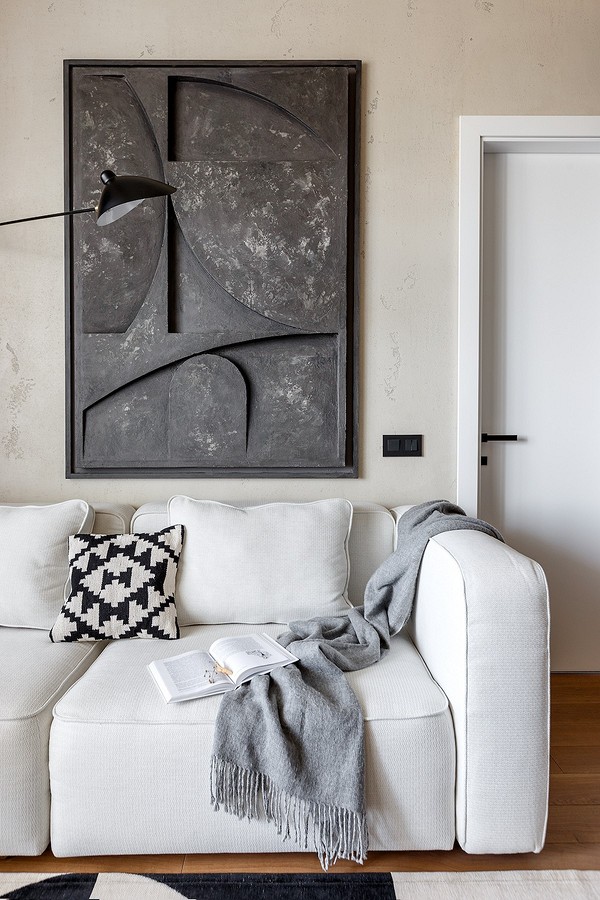 Елегантний білий шкіряний диван в мінімалістичному інтер'єрі з дерев'яними елементами декору.