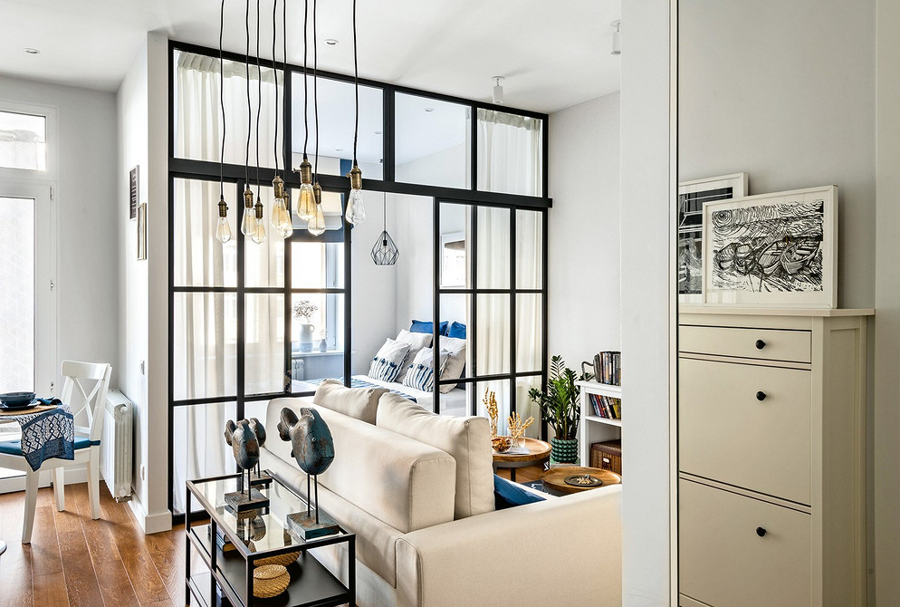 Невеликий білий диван в спальні з рожевими акцентами та декоративними подушками.