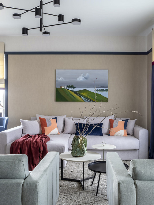 Простора вітальня з великим кутовим білим диваном та панорамними вікнами.