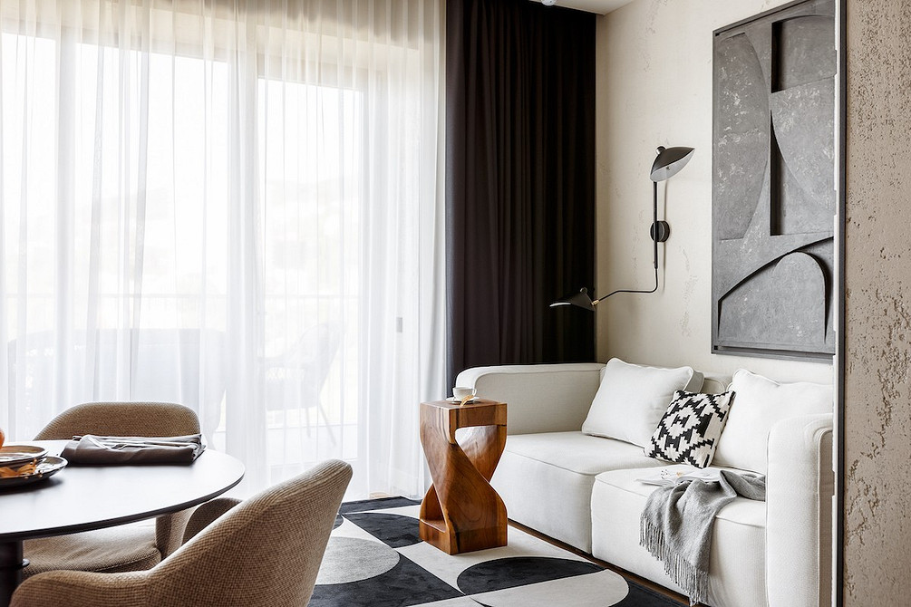 Просторий білий диван з м'якими подушками в мінімалістичному інтер'єрі кімнати