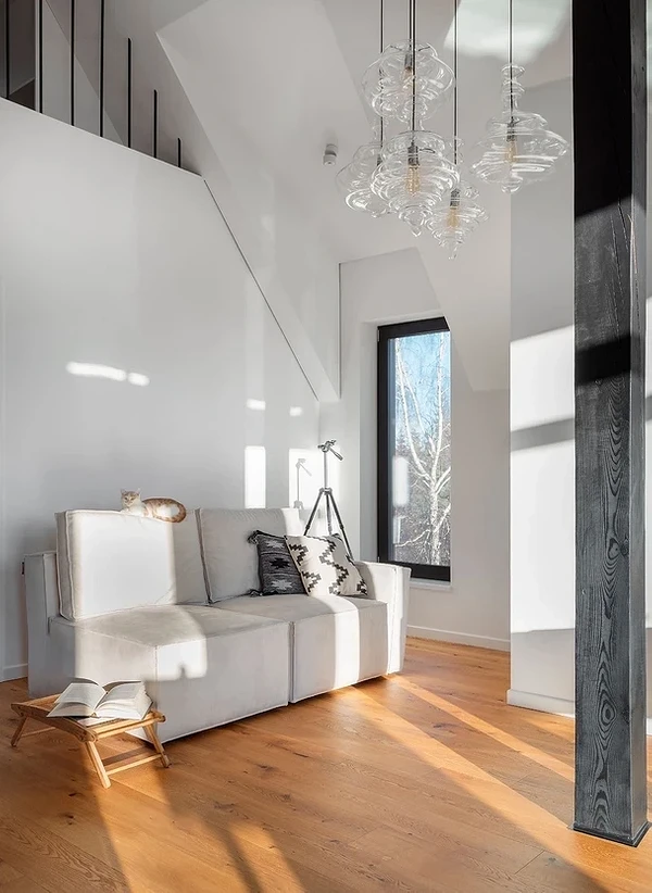 Білий диван у скандинавському стилі з дерев'яними ніжками в світлій вітальні.