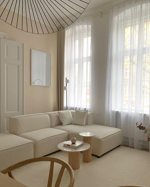 Вітальня з бежевим диваном, шторами та елементами декору в гармонійній кольоровій гамі.