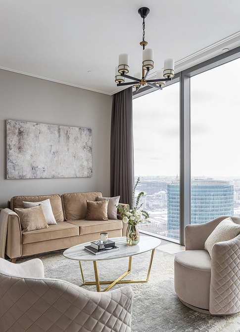 Затишний куточок для читання з бежевим диваном, торшером та книжковою полицею.