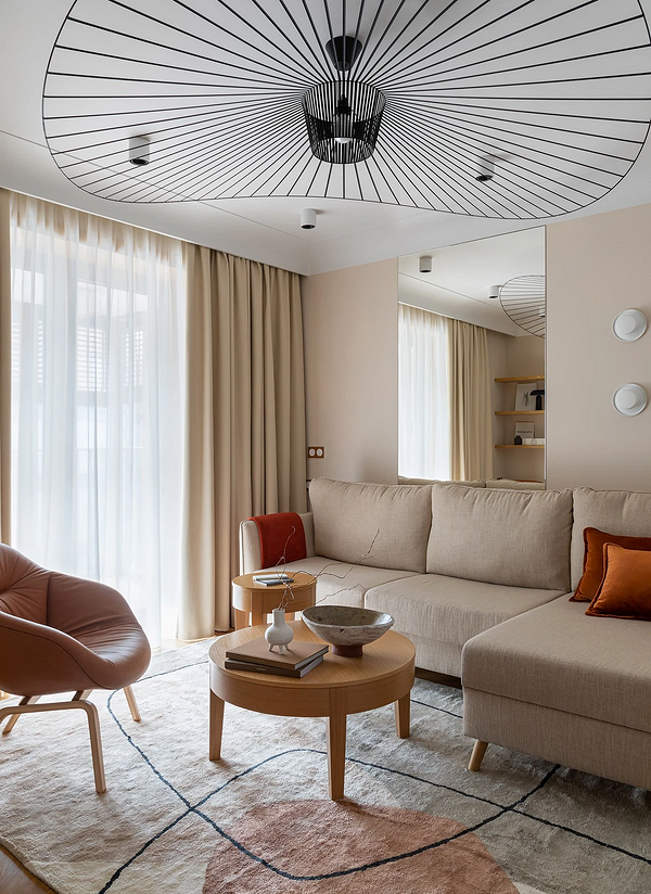 Бежевий диван з велюровою оббивкою у вітальні з декоративними світильниками