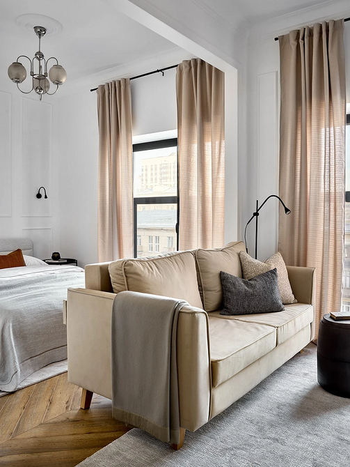 Кутовий бежевий диван з подушками різних відтінків в світлій кімнаті, дизайн інтер'єру.