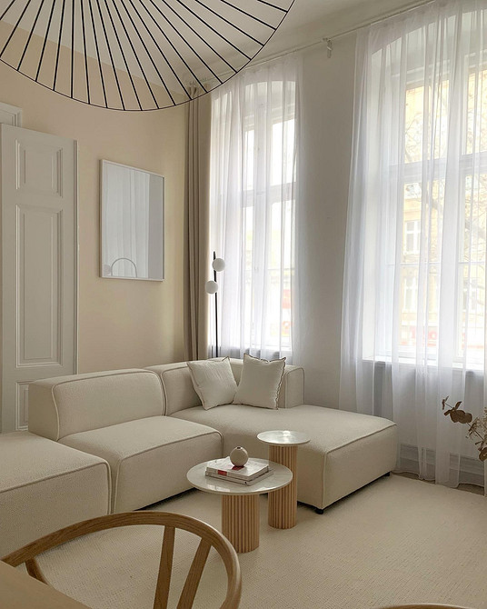 Затишна вітальня з бежевим диваном, декоративними подушками та килимом