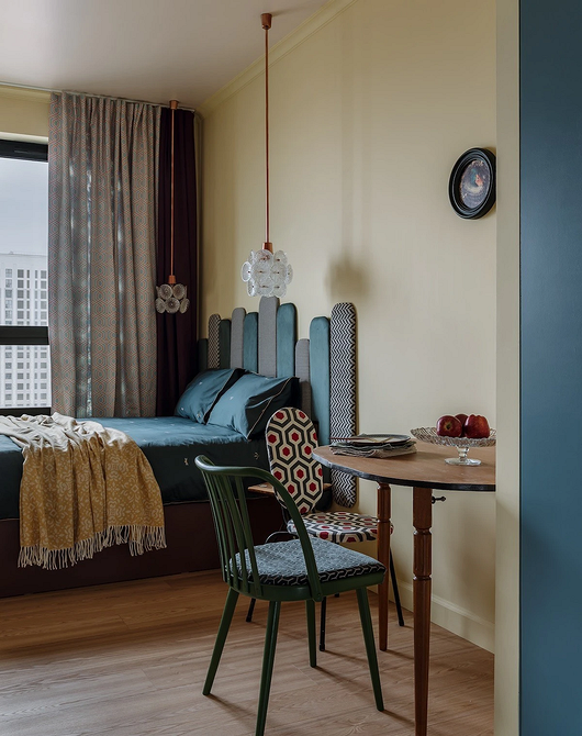 Еклектичний кабінет: книжкова шафа з антикваріатом, сучасне крісло, килим з геометричним малюнком.