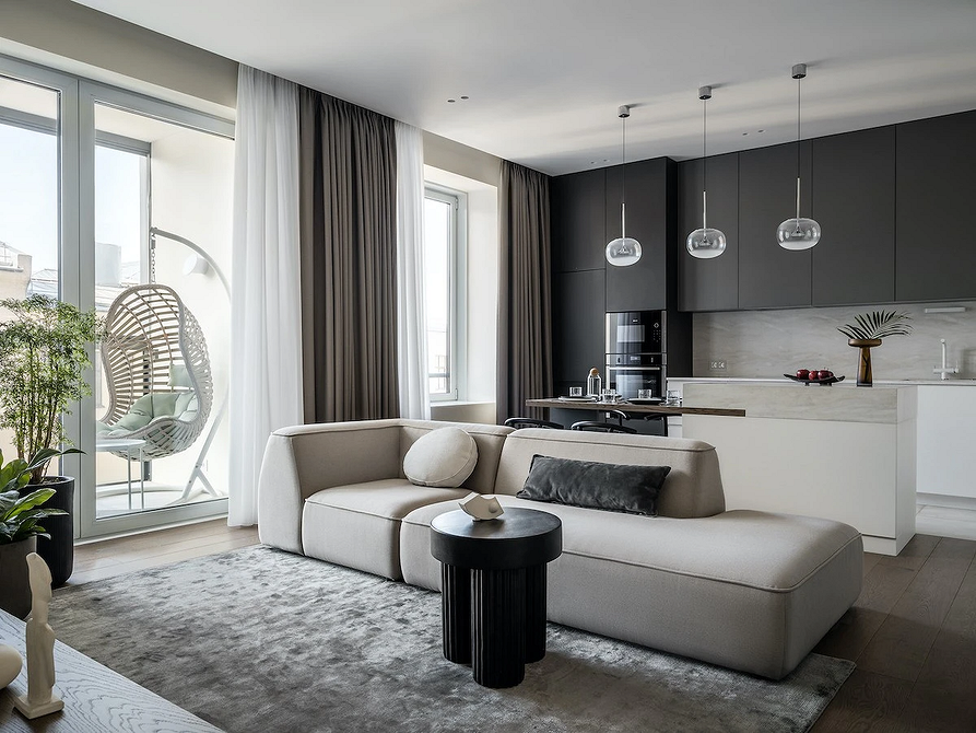 Монохромний дизайн вітальні з акцентним сірим диваном і декоративними подушками, плавні лінії в інтер'єрі.