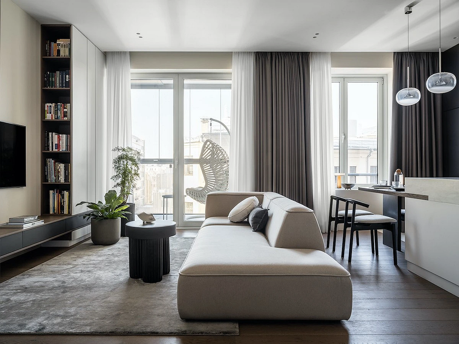 Монохромний диван з декоративними рослинами у вітальні з великим вікном.