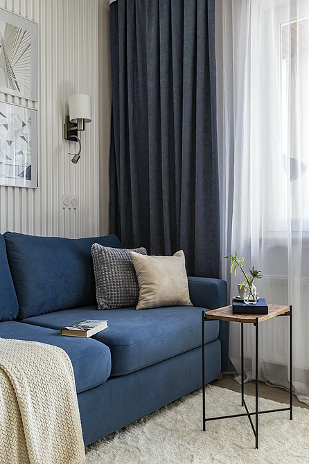Монохромний інтер'єр вітальні з акцентним диваном та декоративними подушками.