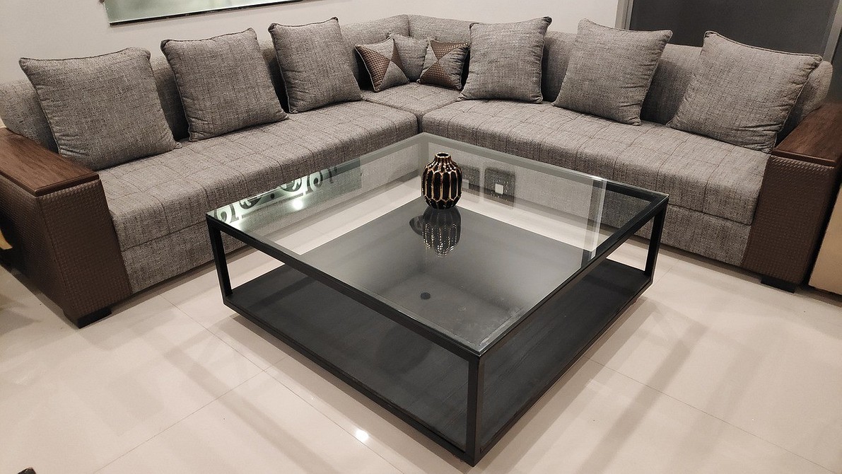 Темний диван з великою кількістю подушок різних текстур і кольорів у кімнаті.