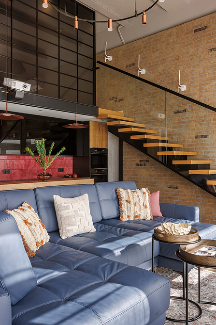 Елегантний темний диван в інтер'єрі з акцентною стіною та сучасним освітленням