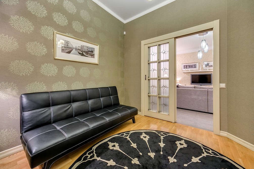 Стильний темний диван мінімалістичного дизайну з дерев'яними ніжками в інтер'єрі.