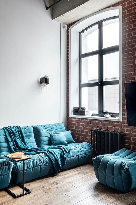 Бірюзовий диван в інтер'єрі з великою кількістю подушок різних кольорів та текстур
