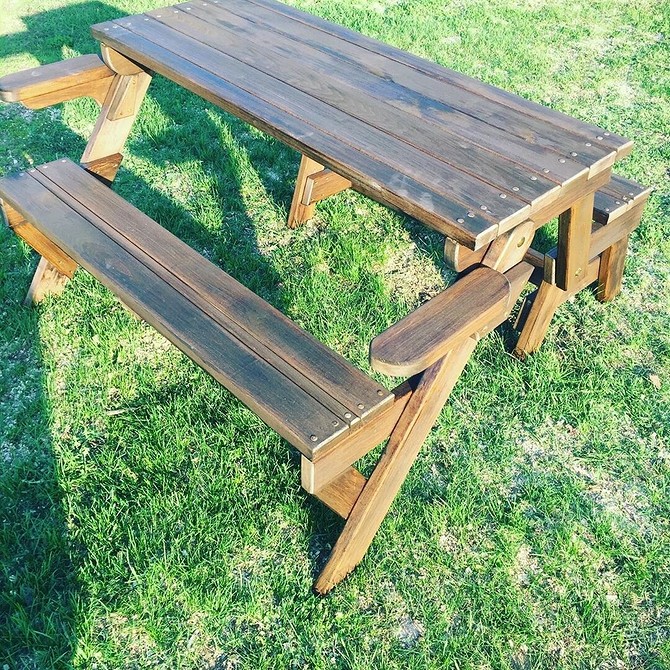 Пошкоджені садові меблі очікують відновлення: старі дерев’яні стільці на газоні.