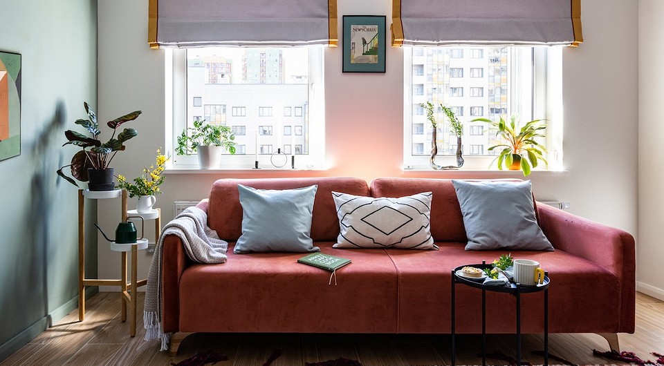 Стильний диван на ніжках в сучасному інтер'єрі вітальні з килимом та декором.