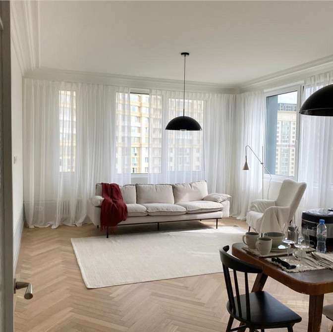 Диван з велюровою оббивкою на дерев'яних ніжках в класичному інтер'єрі.