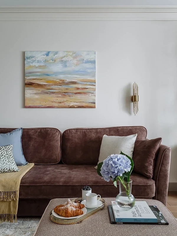 Коричневий диван з подушками різних відтінків у скандинавському інтер'єрі