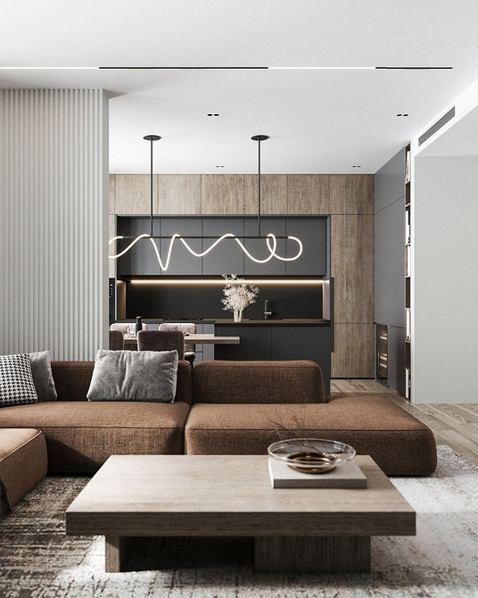 Коричневий диван з подушками різних відтінків в інтер'єрі з великим вікном