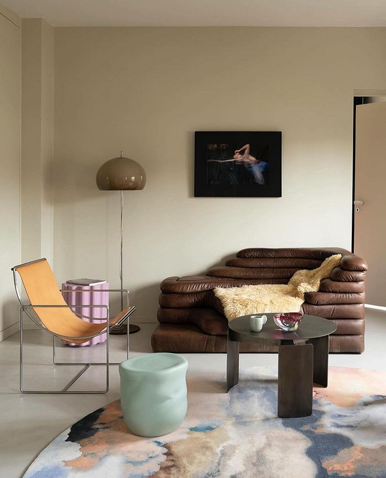 Коричневий диван з подушками різних відтінків у вітальні з рослинами.