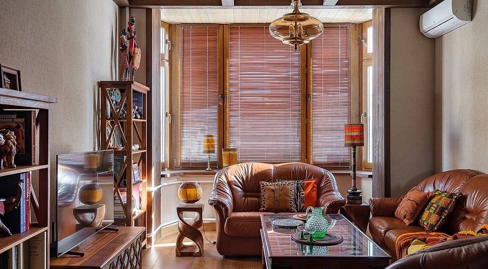 Коричневий диван в інтер'єрі вітальні з дерев'яними елементами та килимом