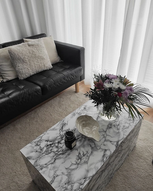 Інтер'єр з невеликим шкіряним диваном та килимом в гармонійній колірній гамі.