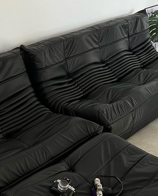 Вітальня з сірим шкіряним диваном, каміном та книжковими полицями