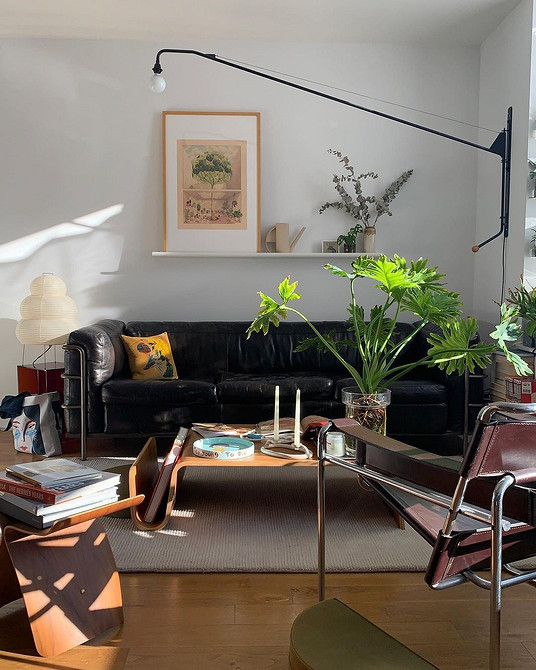 Мінімалістичний дизайн вітальні з чорним шкіряним диваном та білою стіною