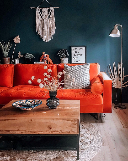 Комфортний червоний диван в інтер'єрі з книжковими полицями та зеленими рослинами