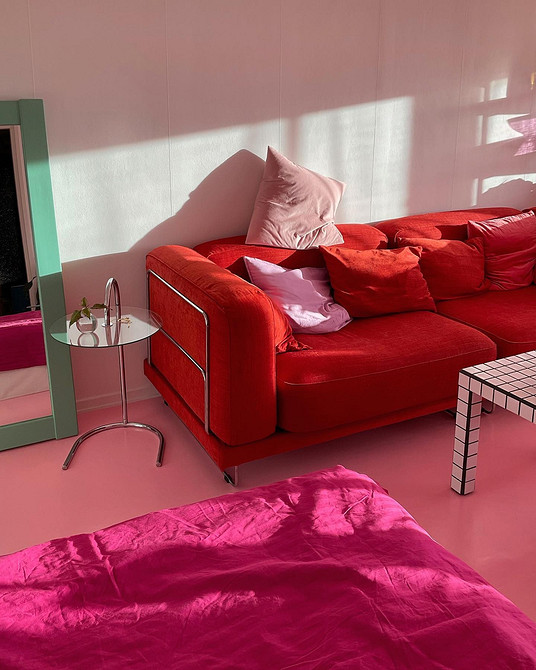 Стильний інтер'єр вітальні з червоним диваном та чорно-білими фотографіями на стінах.