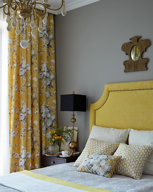 Світла спальня з ліжком з м'якою спинкою, оббитою світлим меблевим текстилем.