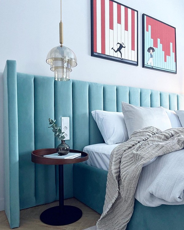 Стильна спальня з ліжком з м'якою спинкою, оббитою тканиною нейтрального кольору.